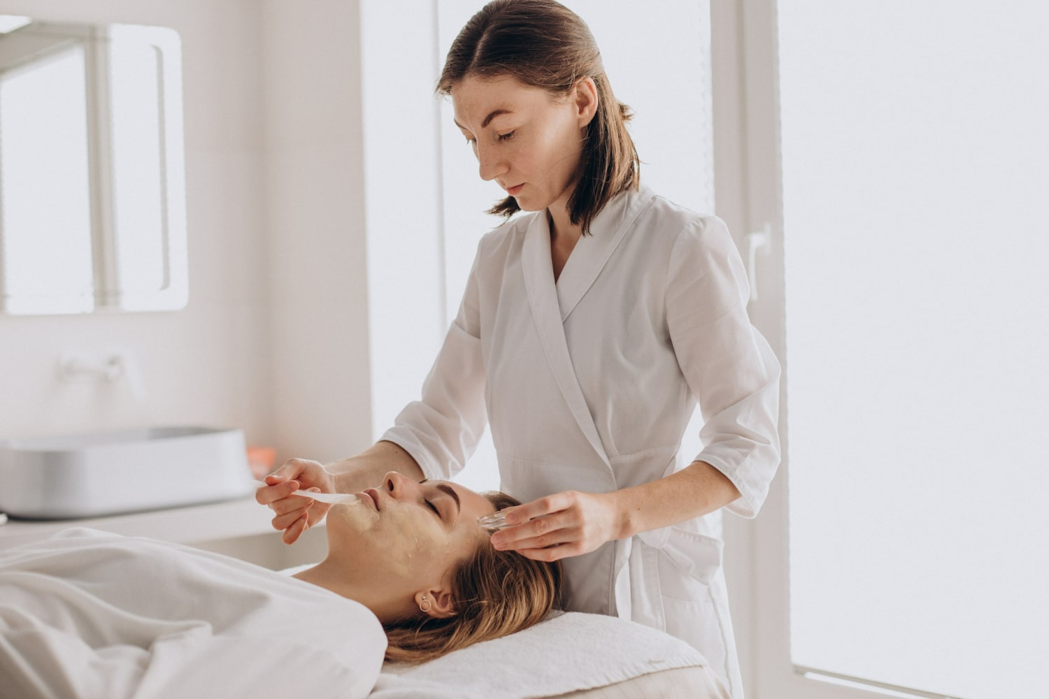 esteticista atendendo uma cliente com tratamentos faciais